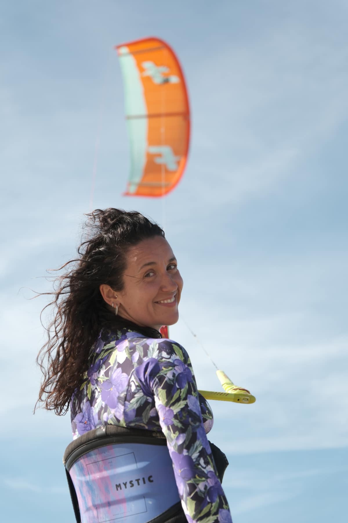 Woman smiling with an orange kite flying behind her in Brazil