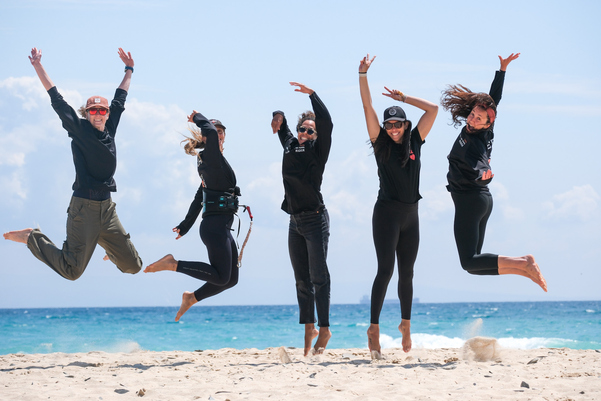 Women jumping together on the beach by the ocean